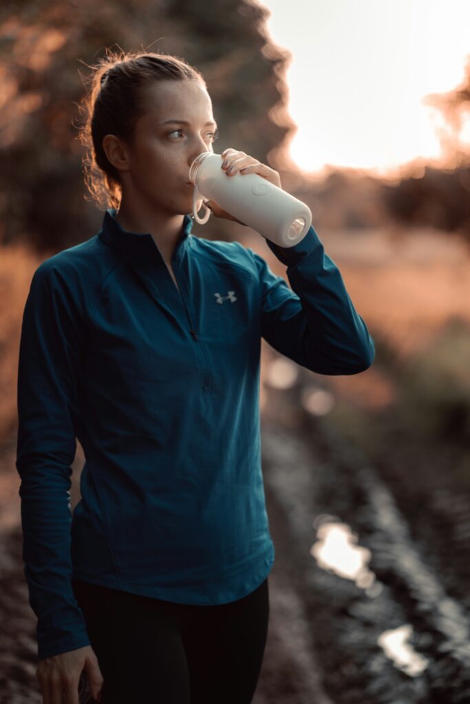 Current image: female runner drinking a protein shake after a training run outdoors