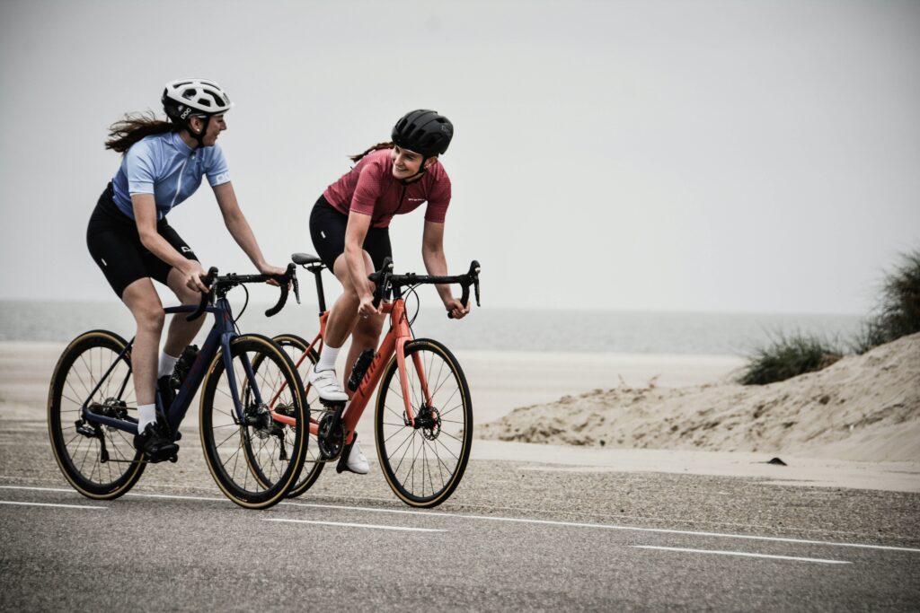 Current image: two cyclists riding together on a coastal road