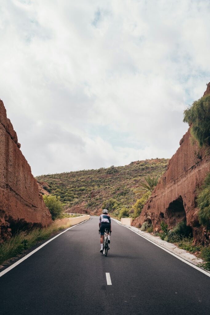 Current image: cyclist riding alone on an open road through a rocky canyon