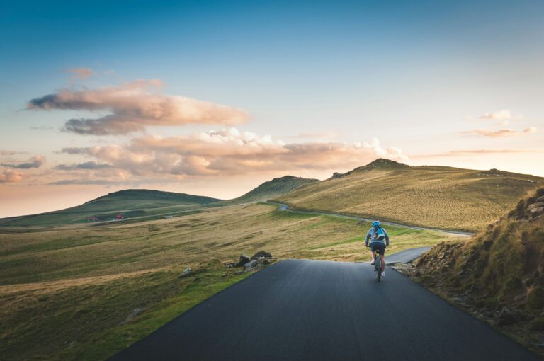 cyclist riding a road bike through open hills at sunset
